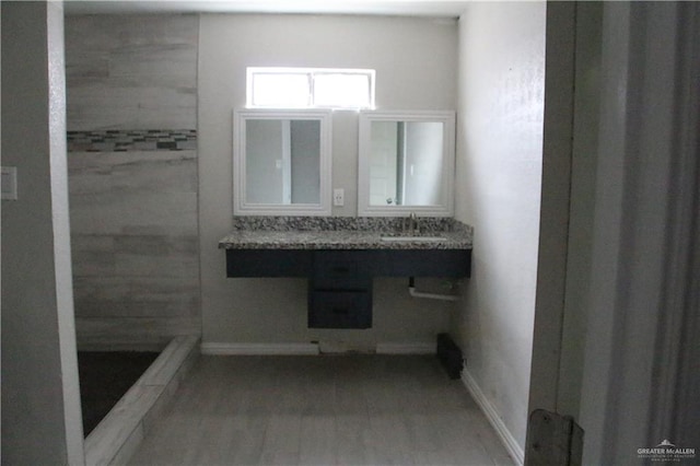 bathroom with hardwood / wood-style flooring, a shower, and sink