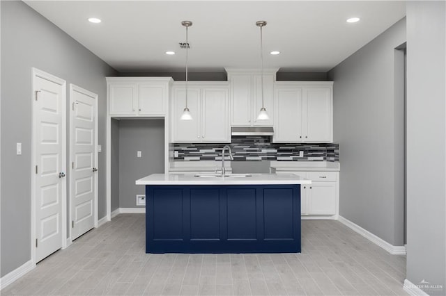 kitchen with a center island with sink, decorative light fixtures, sink, and tasteful backsplash