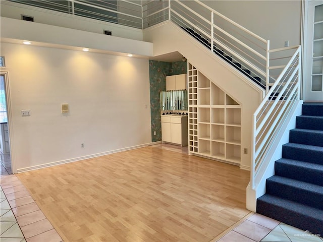 unfurnished living room with a high ceiling and light hardwood / wood-style floors