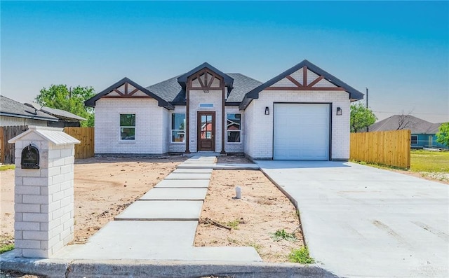 view of front of house with a garage, brick siding, concrete driveway, and fence