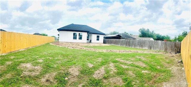 back of property featuring a fenced backyard, a yard, and stucco siding