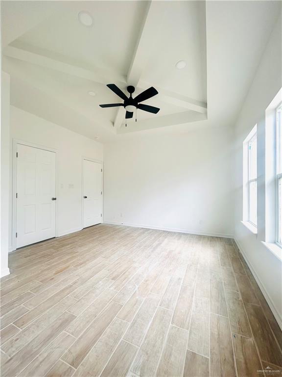 empty room featuring beamed ceiling, baseboards, a ceiling fan, and wood finished floors