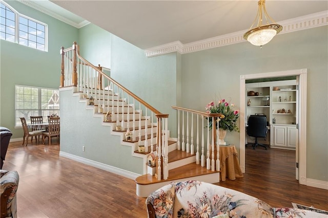 stairway with crown molding and wood-type flooring