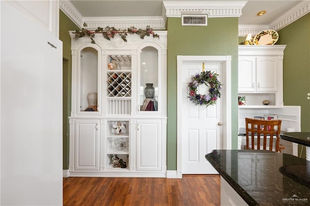 interior space featuring ornamental molding, dark hardwood / wood-style floors, white cabinets, and dark stone counters