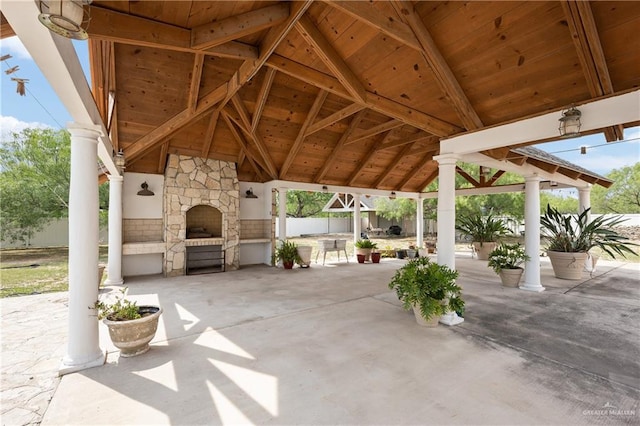 view of patio with a gazebo and an outdoor stone fireplace