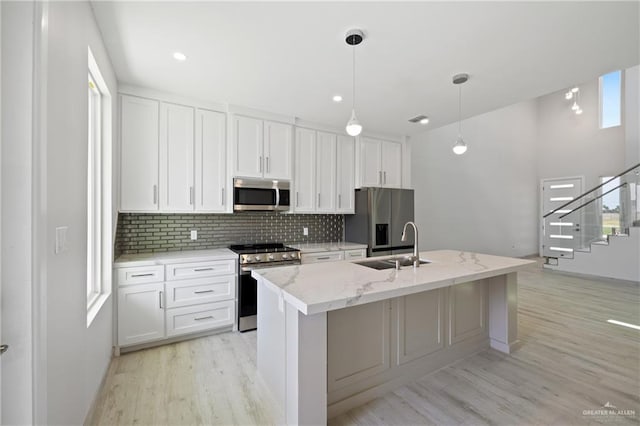 1216 N Lincoln Ave, San Juan, TX 78589 - kitchen featuring stainless steel appliances, light wood-style floors, tasteful backsplash, a sink, and white cabinetry