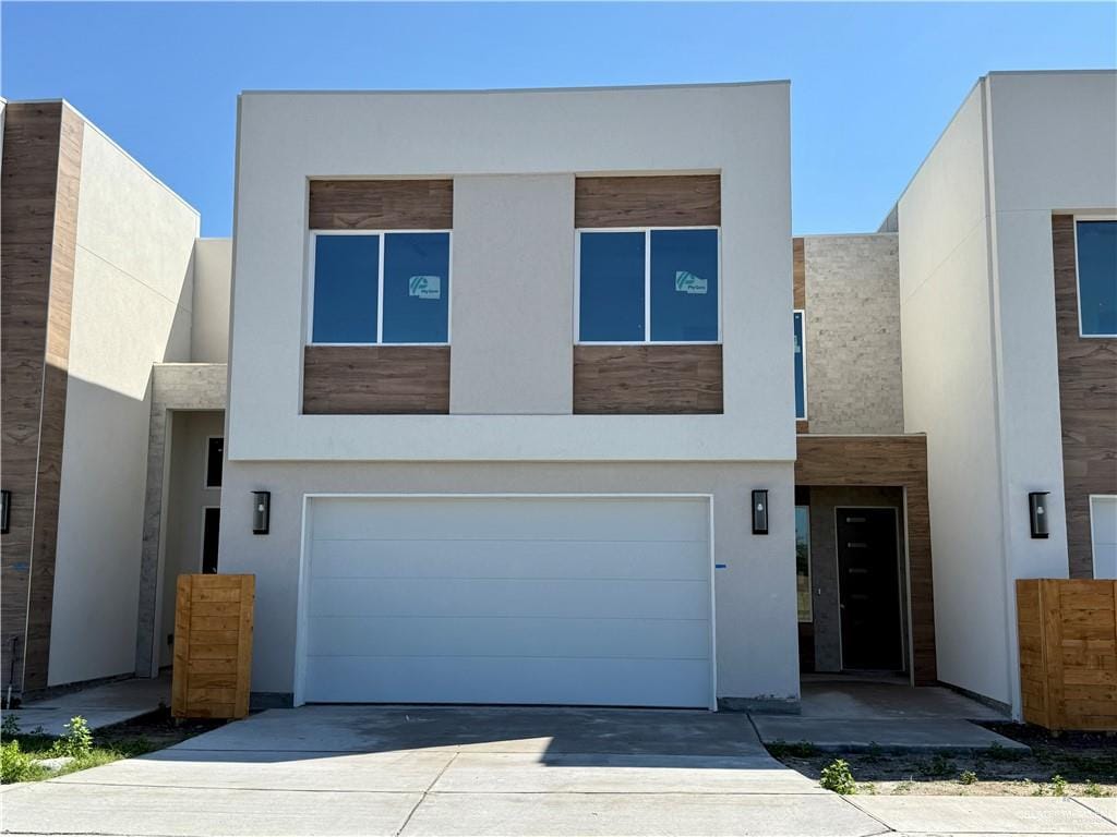 modern home with driveway, an attached garage, and stucco siding