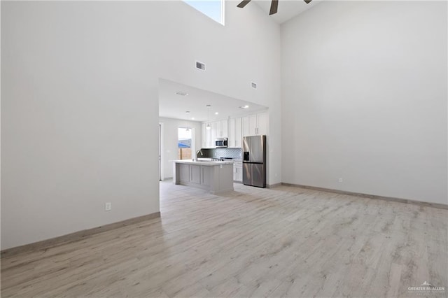 1216 N Lincoln Ave, San Juan, TX 78589 - unfurnished living room with ceiling fan, light wood-style floors, and baseboards