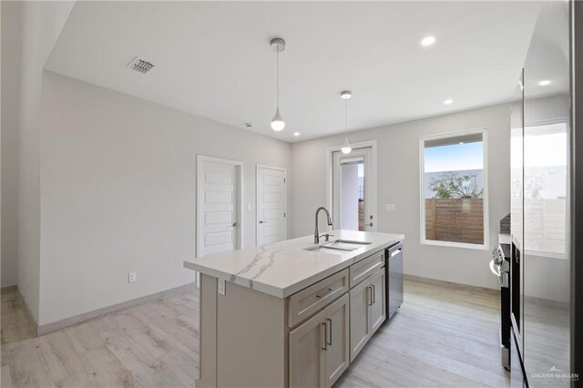 1216 N Lincoln Ave, San Juan, TX 78589 - kitchen with stainless steel appliances, a sink, light wood-style floors, hanging light fixtures, and a kitchen island with sink