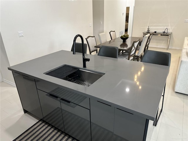 kitchen featuring light tile patterned flooring, gray cabinetry, a spacious island, and sink