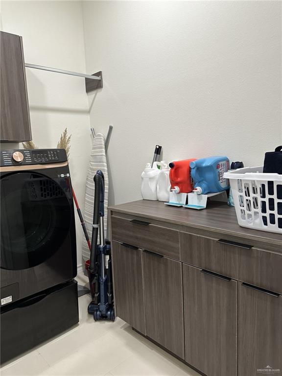 laundry room featuring cabinets, light tile patterned floors, and washer / clothes dryer