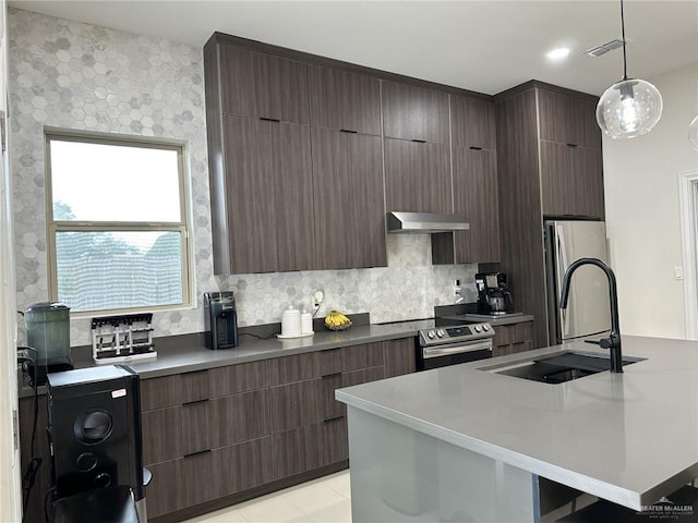 kitchen with appliances with stainless steel finishes, dark brown cabinetry, sink, decorative light fixtures, and range hood