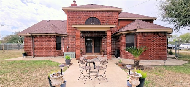 back of house featuring a yard, a patio area, a fire pit, and brick siding