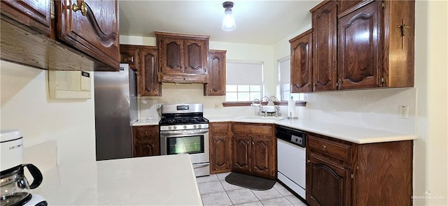 kitchen featuring light tile patterned floors, light countertops, appliances with stainless steel finishes, a sink, and dark brown cabinets