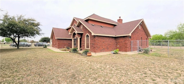 view of side of home with a yard, a chimney, fence, and brick siding