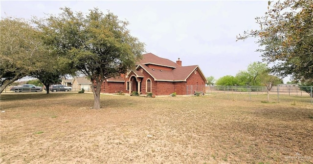 view of front of home featuring a chimney, a front yard, fence, and brick siding