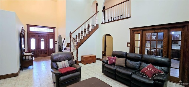 living room with arched walkways, baseboards, a high ceiling, and stairs