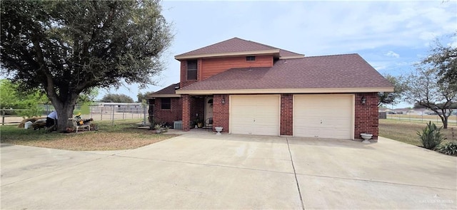 traditional-style house with a garage, brick siding, driveway, and fence