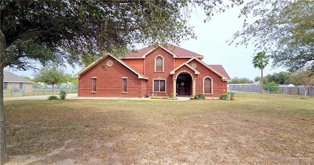 view of front of home with brick siding, a front yard, and fence