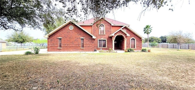 view of front of home featuring a front yard, brick siding, and fence