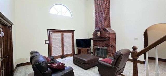 living room with arched walkways, french doors, a high ceiling, a brick fireplace, and baseboards