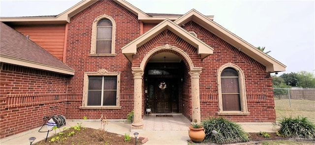 entrance to property with brick siding and fence