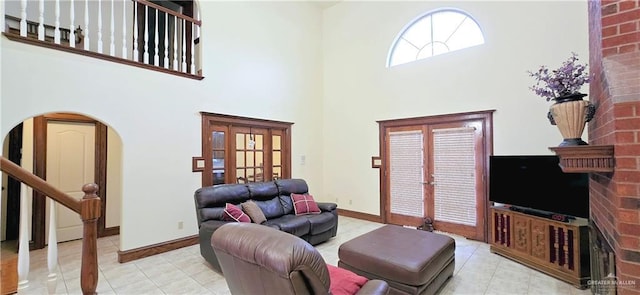 living area with arched walkways, a high ceiling, baseboards, and stairs