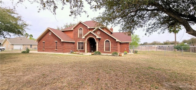 view of front of house featuring a chimney, a front yard, fence, and brick siding