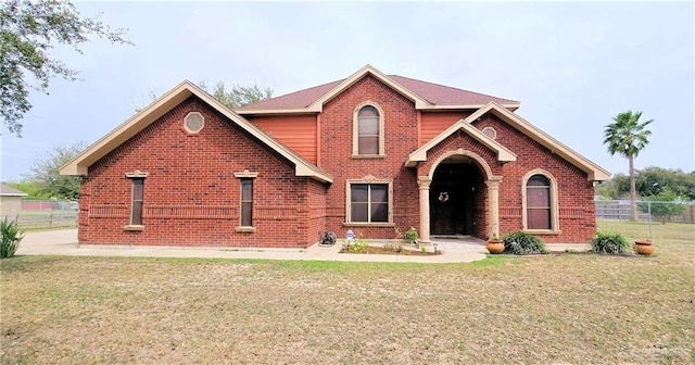 traditional home featuring brick siding, fence, and a front yard