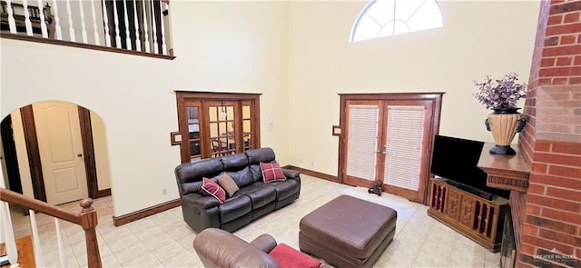 living room featuring arched walkways, french doors, a towering ceiling, and baseboards