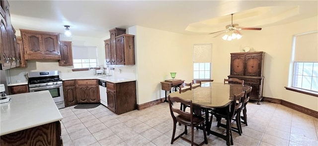 kitchen featuring a tray ceiling, light countertops, gas range, dishwasher, and baseboards