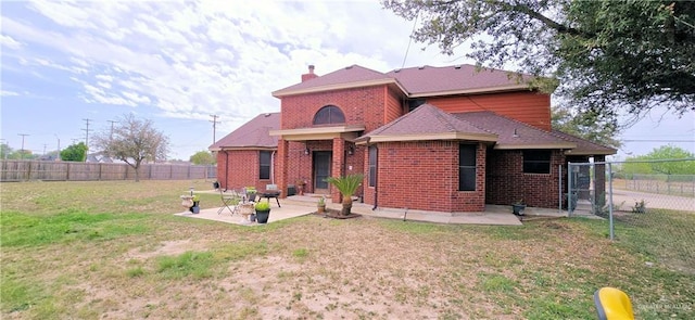 view of front of property with brick siding, a chimney, a front yard, a patio area, and fence