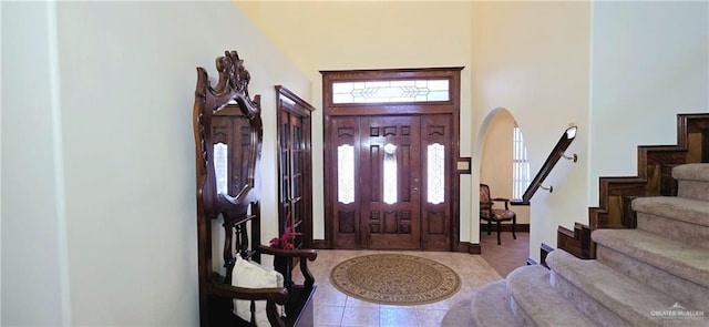 tiled foyer entrance featuring baseboards and stairs