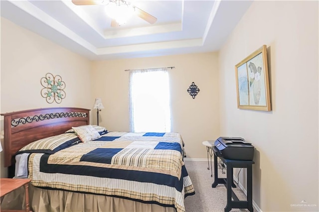 carpeted bedroom featuring ceiling fan and a tray ceiling