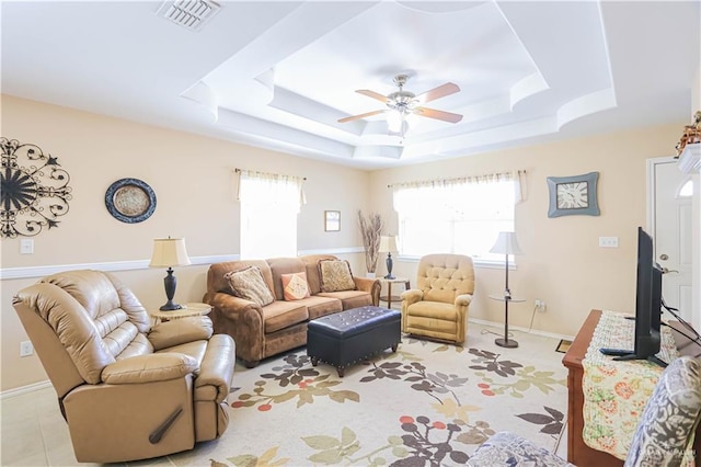 living room with ceiling fan, a healthy amount of sunlight, and a raised ceiling