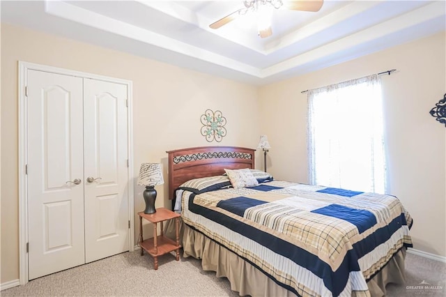 bedroom featuring a closet, carpet floors, ceiling fan, and a tray ceiling