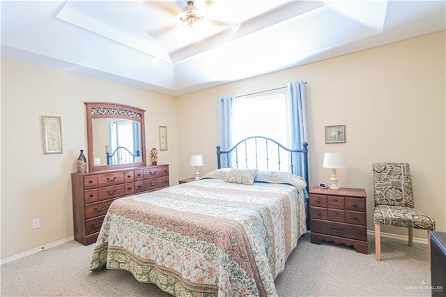 carpeted bedroom featuring ceiling fan and a tray ceiling