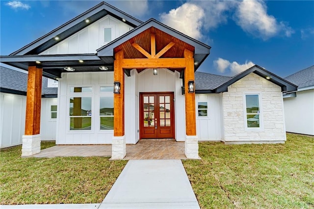 view of exterior entry with a lawn and french doors