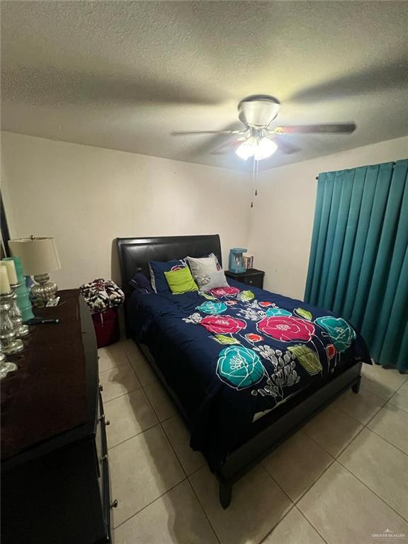 bedroom with light tile patterned floors, a textured ceiling, and a ceiling fan