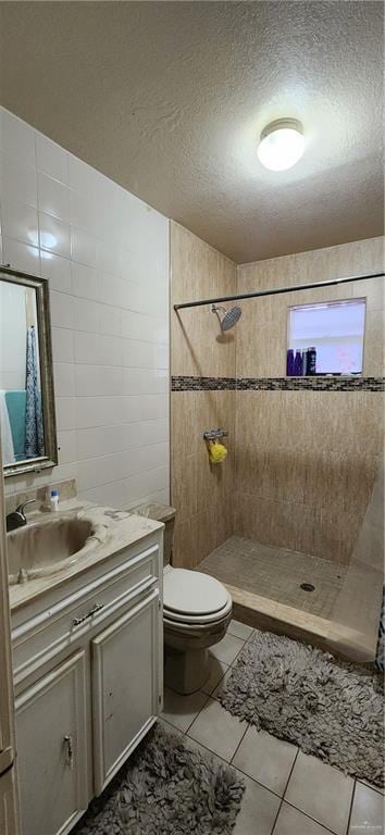 bathroom featuring tile walls, toilet, a tile shower, a textured ceiling, and vanity