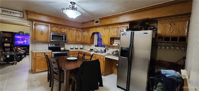 kitchen with light countertops, visible vents, decorative backsplash, appliances with stainless steel finishes, and brown cabinetry