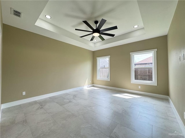 unfurnished room featuring a raised ceiling and ceiling fan