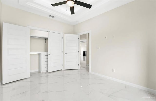 unfurnished bedroom featuring ceiling fan, a tray ceiling, and a closet