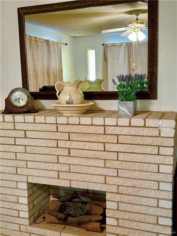 details with a textured ceiling, ceiling fan, and a brick fireplace