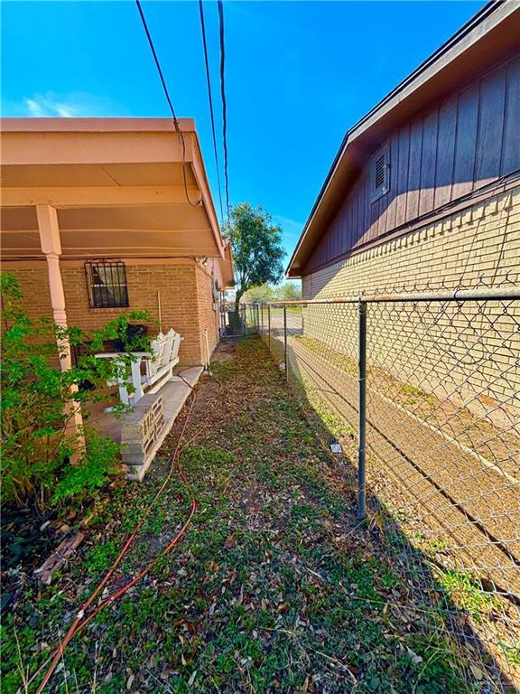 view of side of property with board and batten siding, brick siding, fence, and a patio