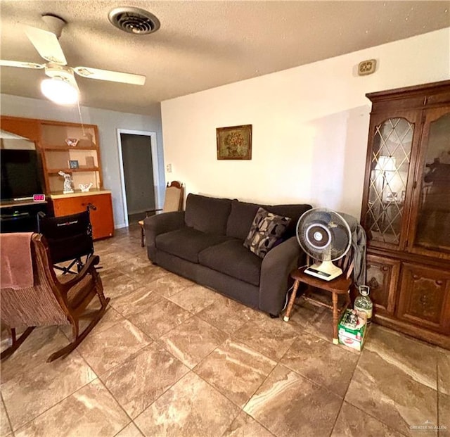 living room with ceiling fan, a textured ceiling, and visible vents