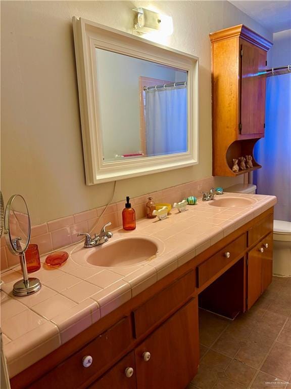 full bath with double vanity, toilet, a sink, and tile patterned floors