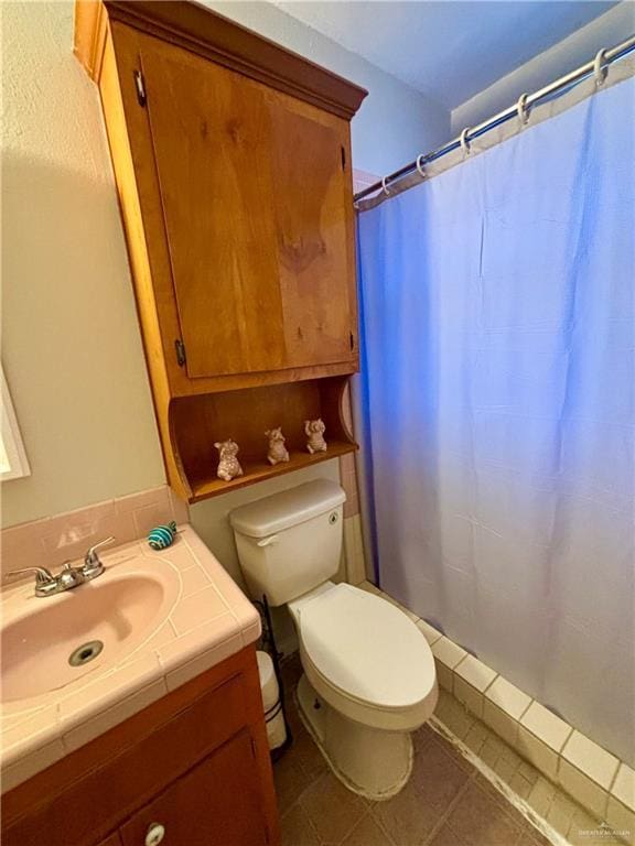 bathroom featuring toilet, curtained shower, tile patterned flooring, and vanity