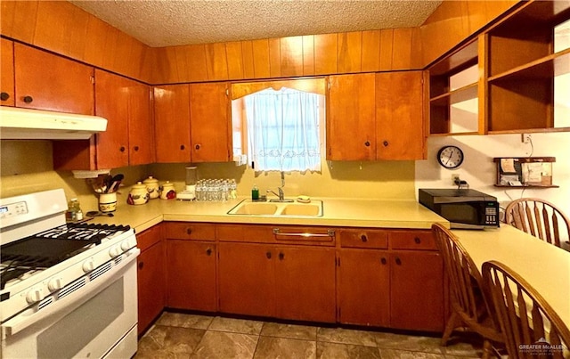 kitchen with light countertops, a sink, under cabinet range hood, and white gas range oven