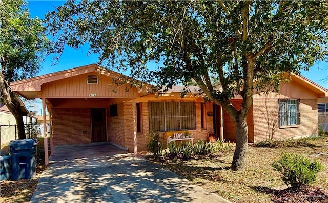 ranch-style home with driveway, an attached carport, and brick siding